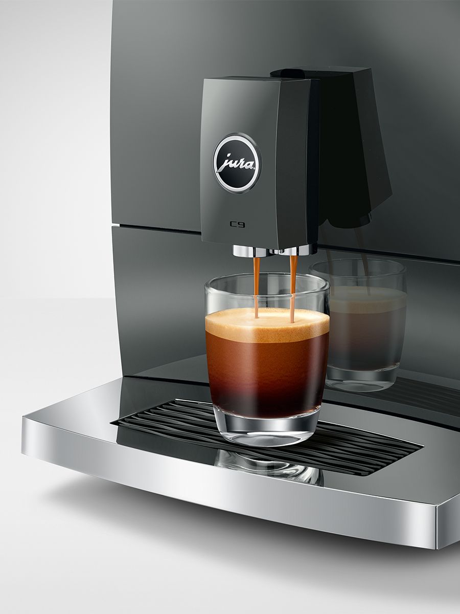 Jura coffee machine dispensing coffee into a glass on a gray background