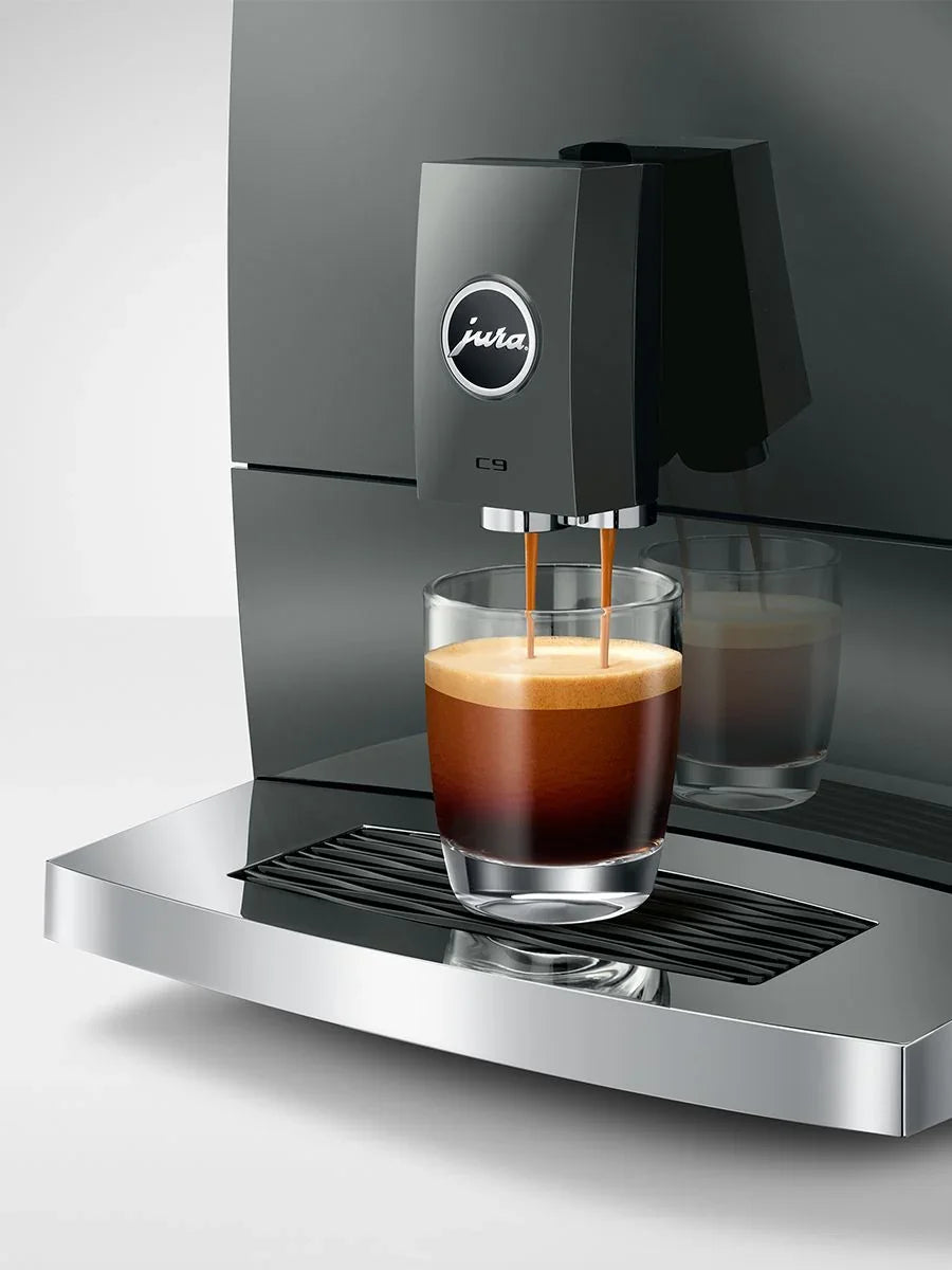 Jura coffee machine dispensing coffee into a glass on a gray background