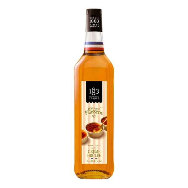 A bottle of 183 Creme Brulee syrup, featuring a golden-amber liquid inside a clear glass bottle with a cream and black label, set against a plain white background.