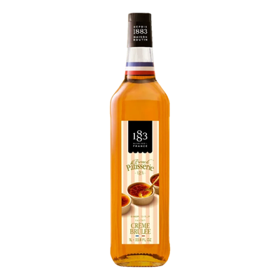 A bottle of 183 Creme Brulee syrup, featuring a golden-amber liquid inside a clear glass bottle with a cream and black label, set against a plain white background.