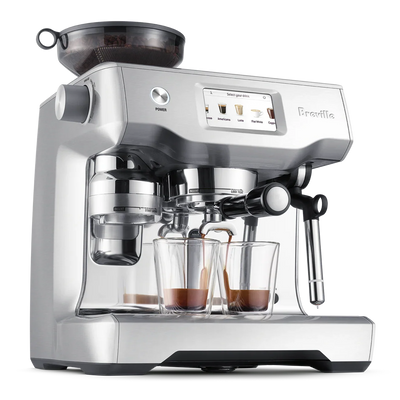 Silver Breville espresso machine with two glass cups on a white background