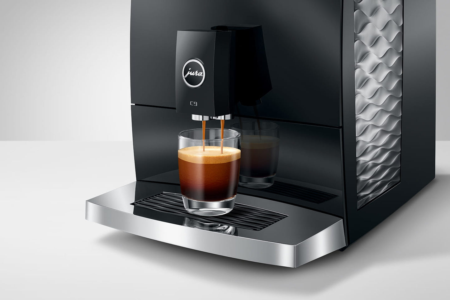 Black coffee machine dispensing coffee into a glass on a white background