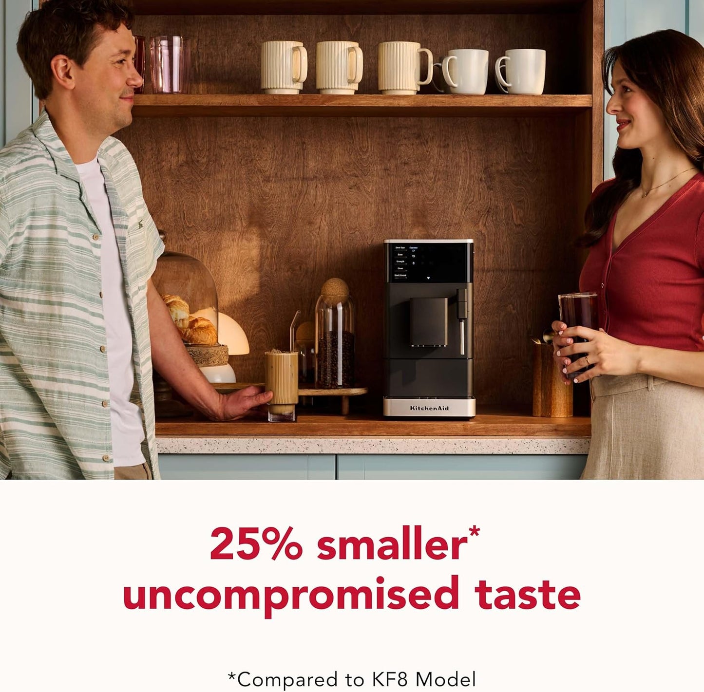 Two people in a kitchen with a coffee machine and cups, featuring text about a smaller model.