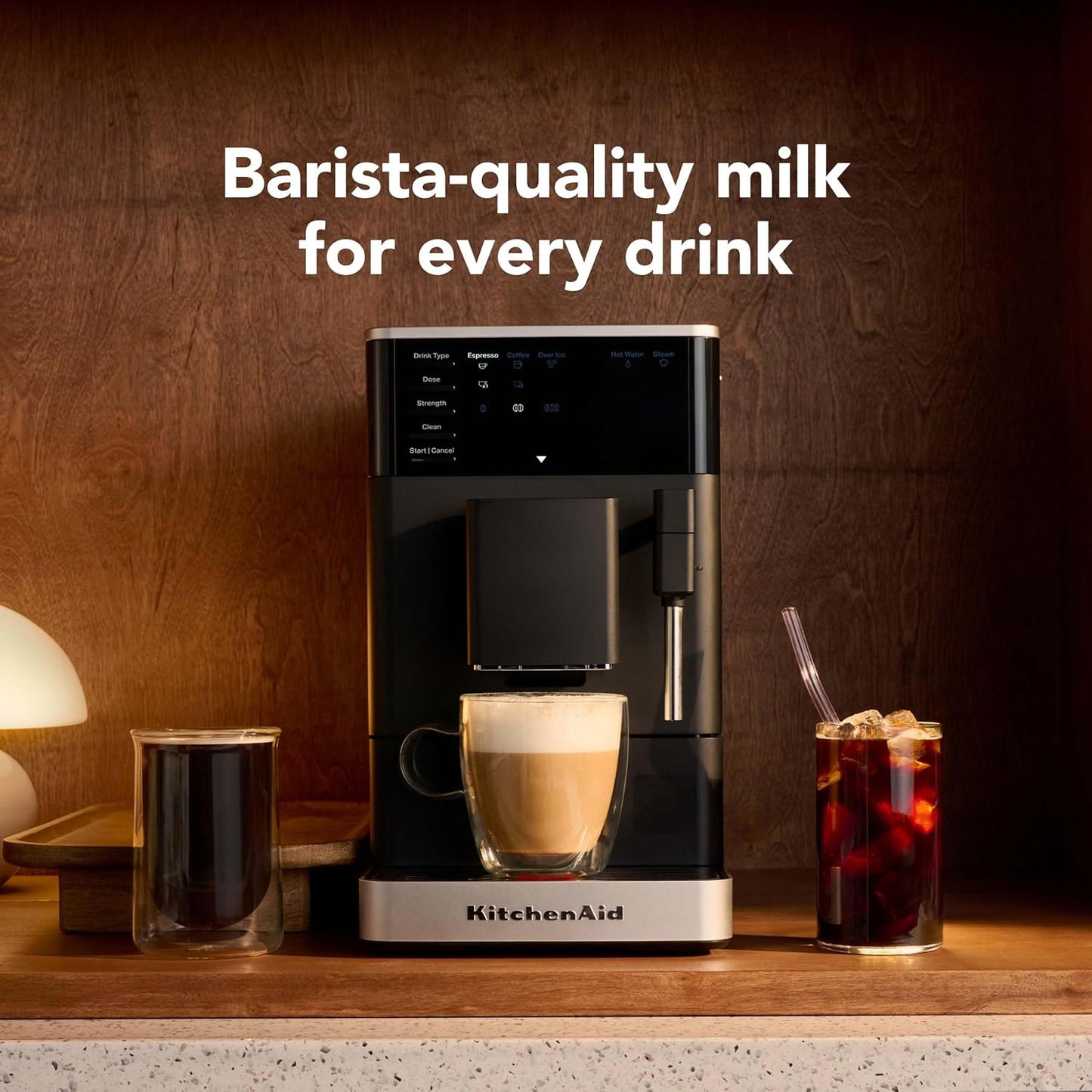 KitchenAid coffee machine with a cup of coffee and a glass of iced drink on a wooden surface.