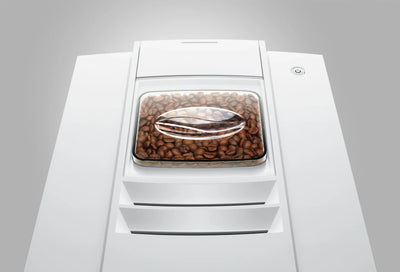 White coffee machine with a clear lid showing coffee beans on a gray background