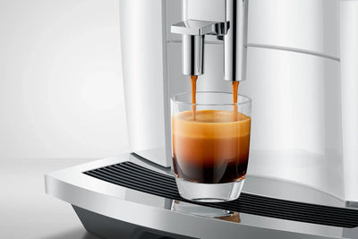 Espresso being poured into a glass from a modern coffee machine.
