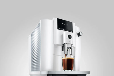 White coffee machine with a glass of coffee on a gray background