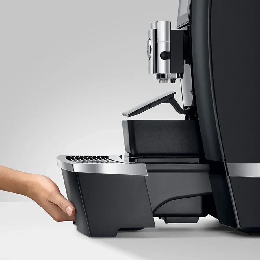 Espresso machine with a hand reaching to open the front panel on a light gray background