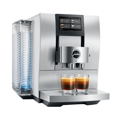 A Jura ESAM coffee machine in stainless steel with a digital touch screen, a water tank on the left, and two glasses of espresso on the drip tray, shown against a solid white background.